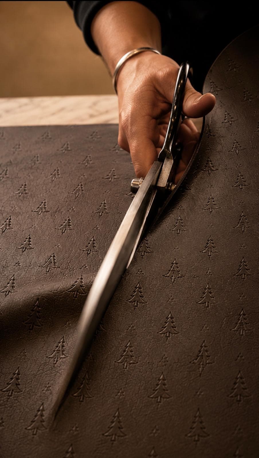 Craftsperson cutting brown leather with the ARAS pine emblem
