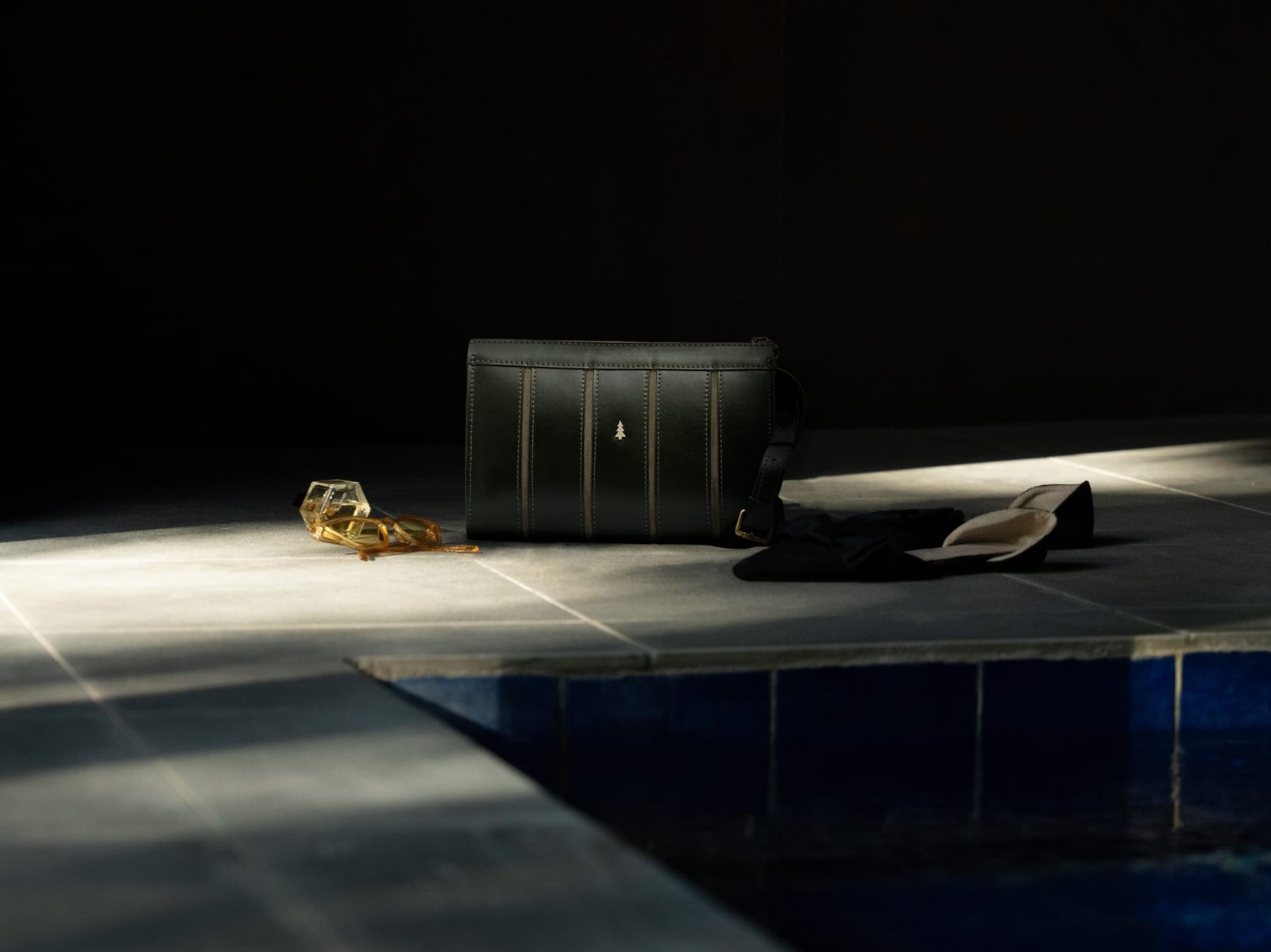 ARAS PINE Calder Clutch — forest green panelled, at the edge of a pool with sunglasses and slippers — leather clutch, handmade in Türkiye